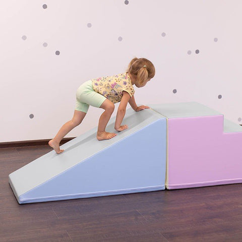 1. Young girl climbing pastel-colored soft play slide and steps in a playroom with polka dot wall