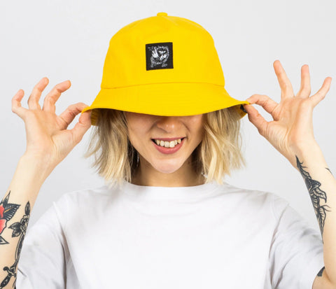 1. Women's yellow Stinky Bucket Hat by Moomin, worn by model with playful pose