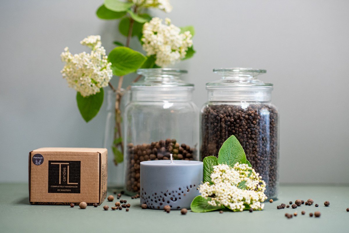 6. TL Candles hand-made soy wax candle with patchouli scent, shown with packaging and natural elements
