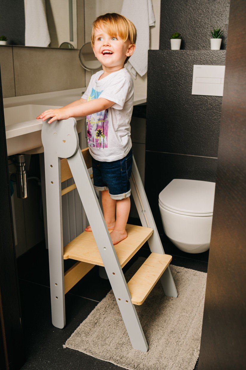 15. Child using grey step stool in bathroom