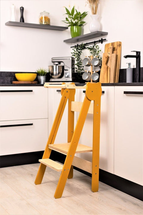 2. Orange foldable step stool placed against white kitchen cabinets