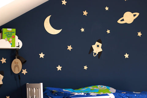 3. Dark blue wall with wooden moon, Saturn, rocket, and stars in a child's room