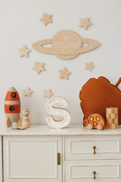 5. White wall with wooden Saturn and stars above cabinet with toys and letter S lamp