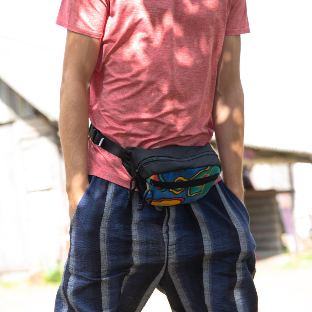 1. Man wearing Drinbags waist bag with colorful pattern and black strap, standing outdoors in casual attire