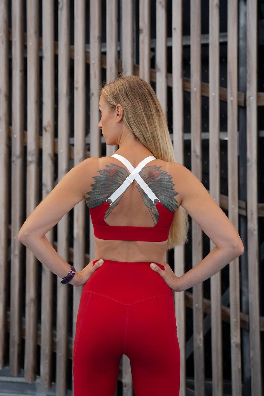 2. Back view of woman wearing Peachlabel 'Cute Cranberry' red sports bra with crisscross straps