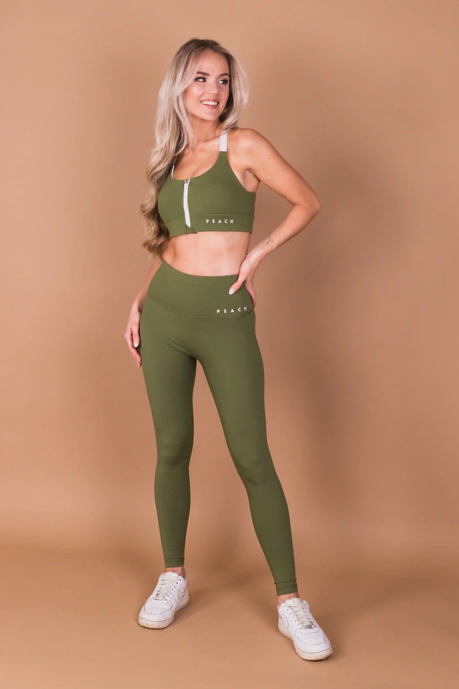 3. Full view of woman in Peachlabel Olive Green Sports Bra and leggings, standing, studio setting