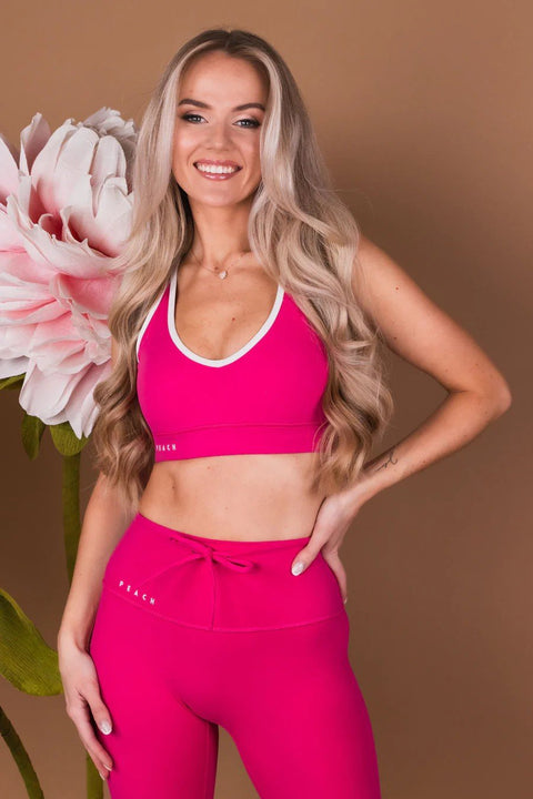 1. Woman wearing Peachlabel Raspberry Dream sports bra and leggings, smiling in a lifestyle setting