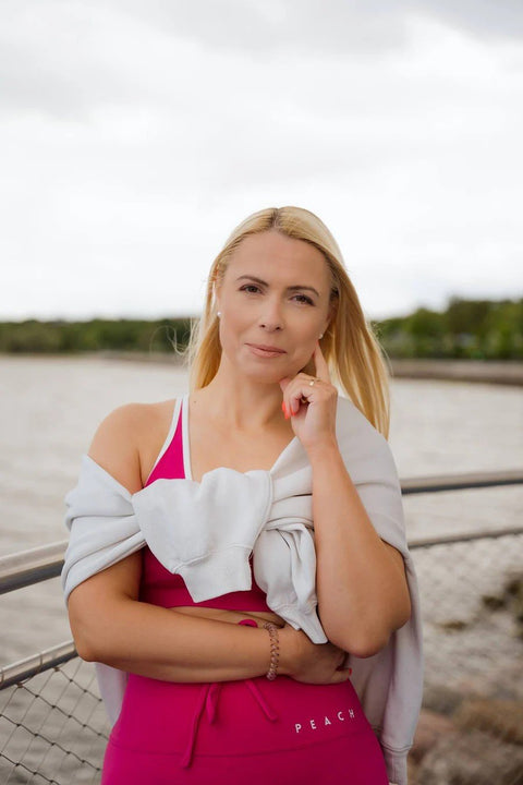 5. Woman in Peachlabel Raspberry Dream sports bra with jacket, standing by a river