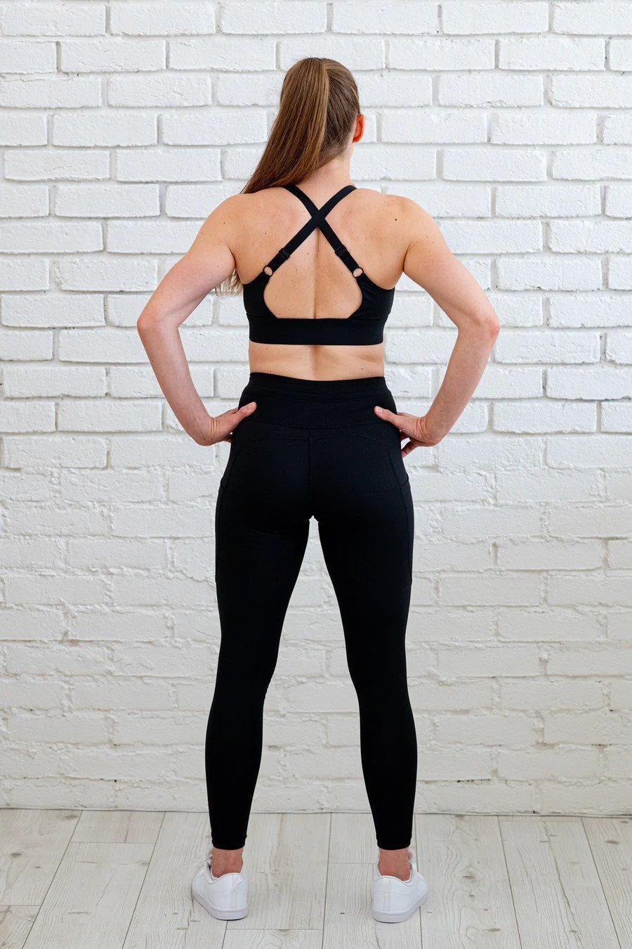 4. Back view of woman wearing Peachlabel 'Zipper Heaven' black sports bra, showing crisscross straps