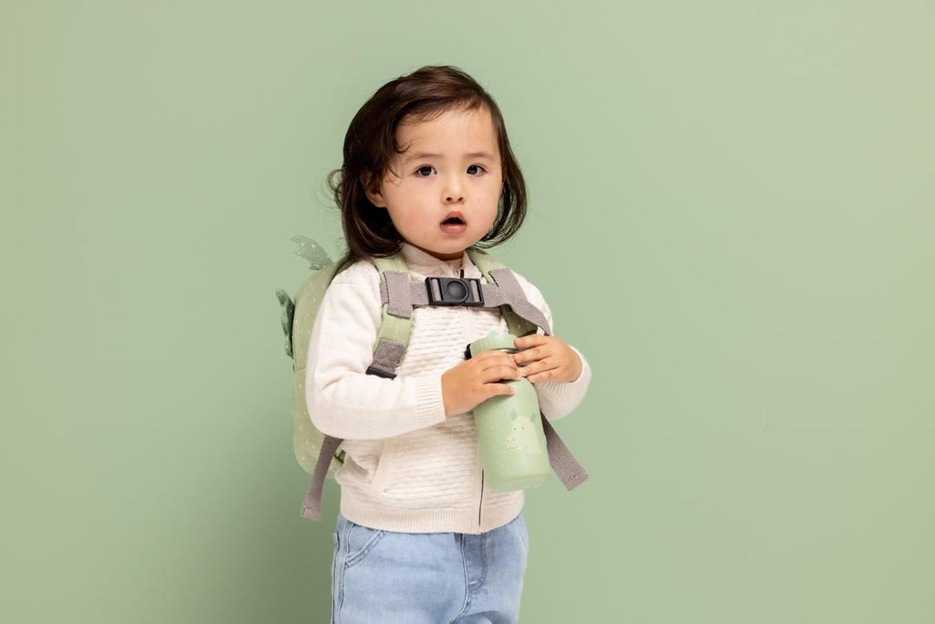 1. Child holding green dragon-themed bottle with backpack, light green background