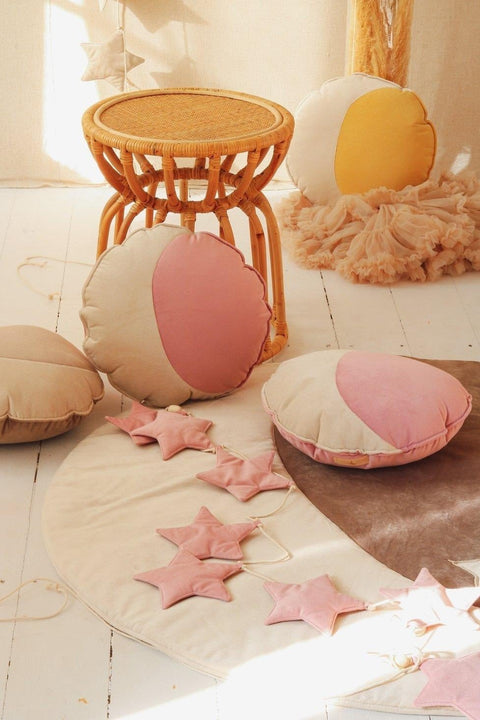 3. Soft pink star garland with round cushions and wicker stool in warm-toned room