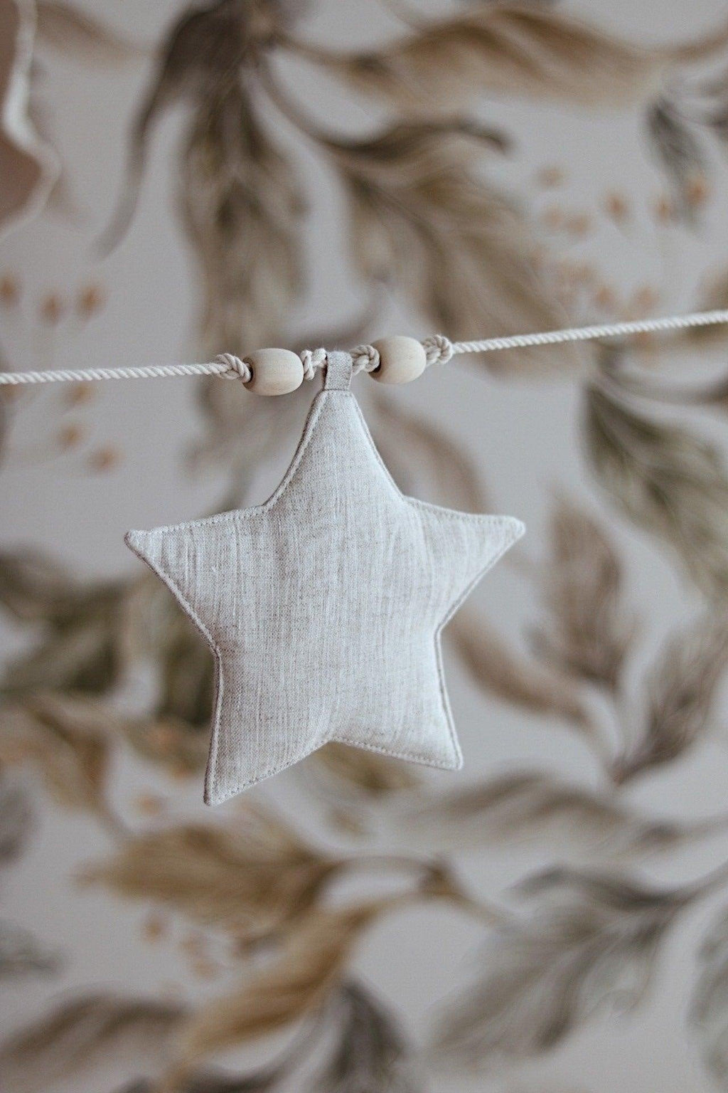 8. Close-up of linen star with wooden beads on string against floral wallpaper