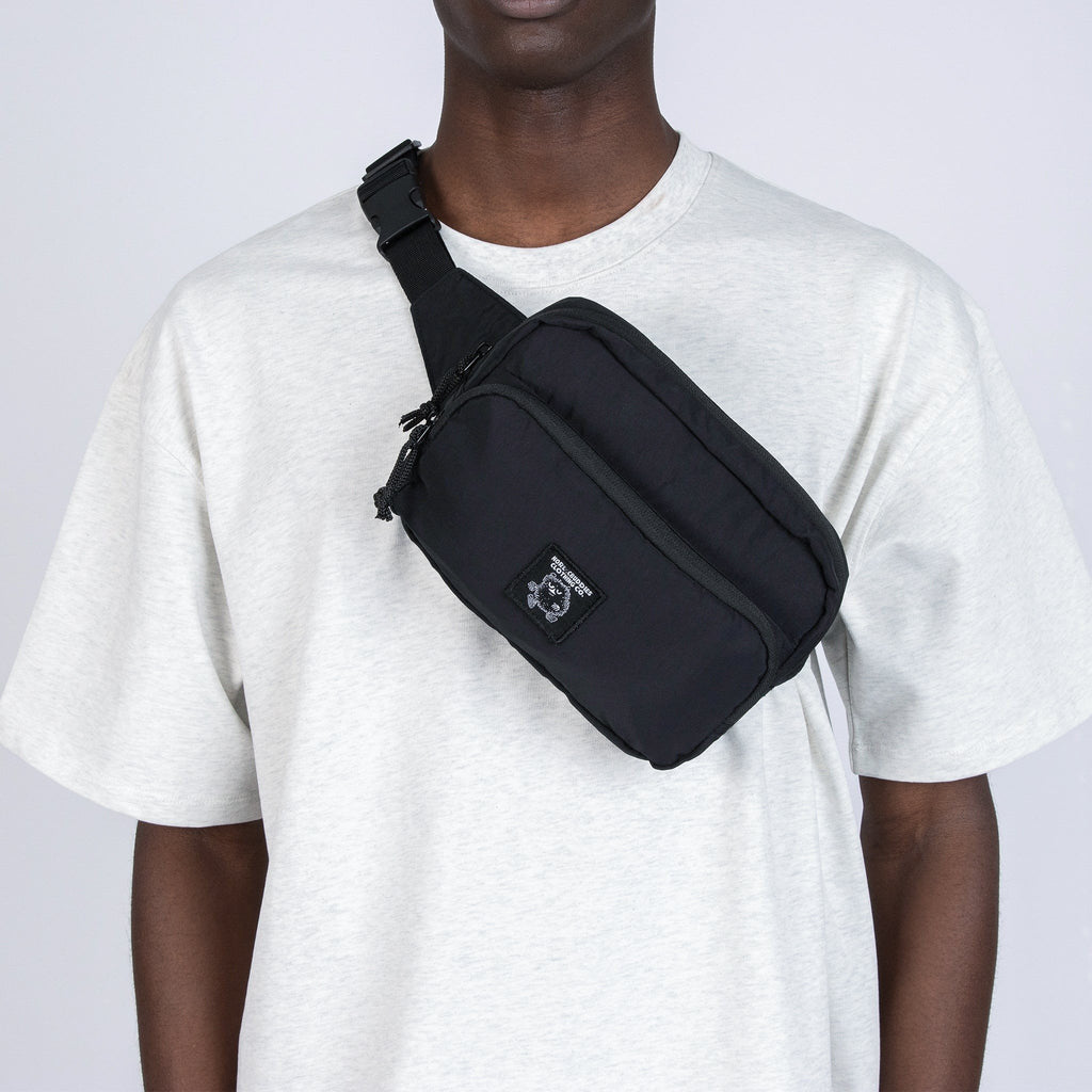 1. Unisex black Stinky Retro Waist Bag by Moomin worn crossbody by male model in studio