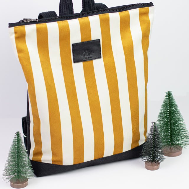10. Muni striped mustard and white backpack in studio with decorative trees