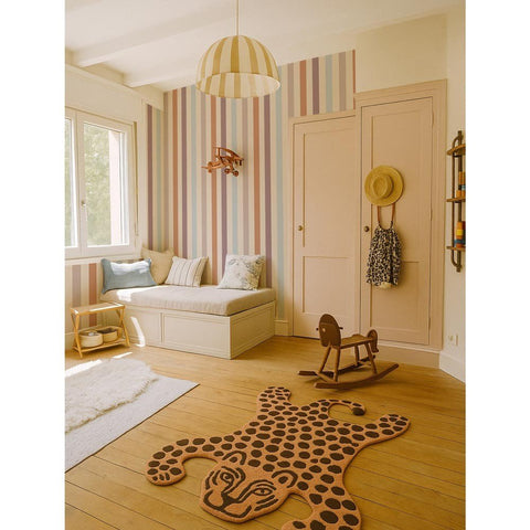 1. Children's room with warm striped wallpaper in beige, blue, and orange tones, featuring a cozy seating area, wooden rocking horse, and decorative rug