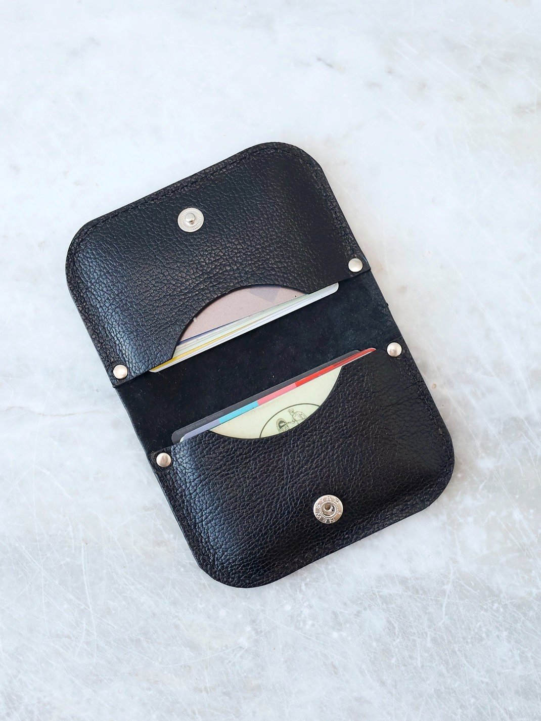 1. Open black textured leather wallet by TOKS VISOKS showing card slots on marble surface