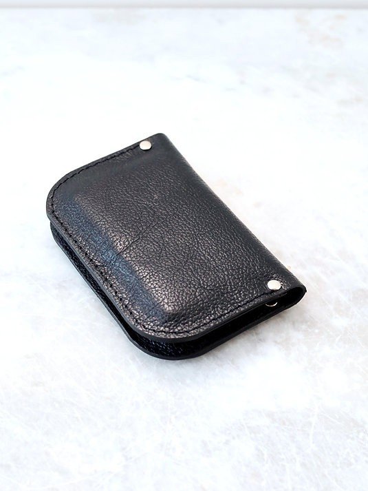 2. Closed black textured leather wallet by TOKS VISOKS on marble background