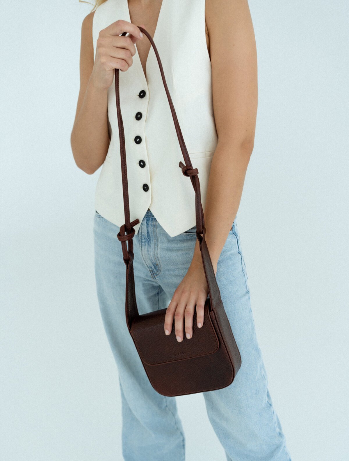 1. Women's brown MUSA crossbody bag by Lava Flow, worn with casual outfit, showcasing adjustable strap and minimalist design