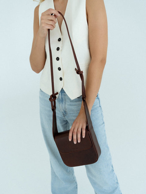 1. Women's brown MUSA crossbody bag by Lava Flow, worn with casual outfit, showcasing adjustable strap and minimalist design