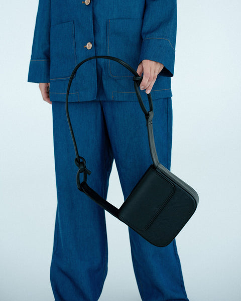 3. Black MUSA crossbody bag by Lava Flow, held by model in blue denim outfit, studio setting
