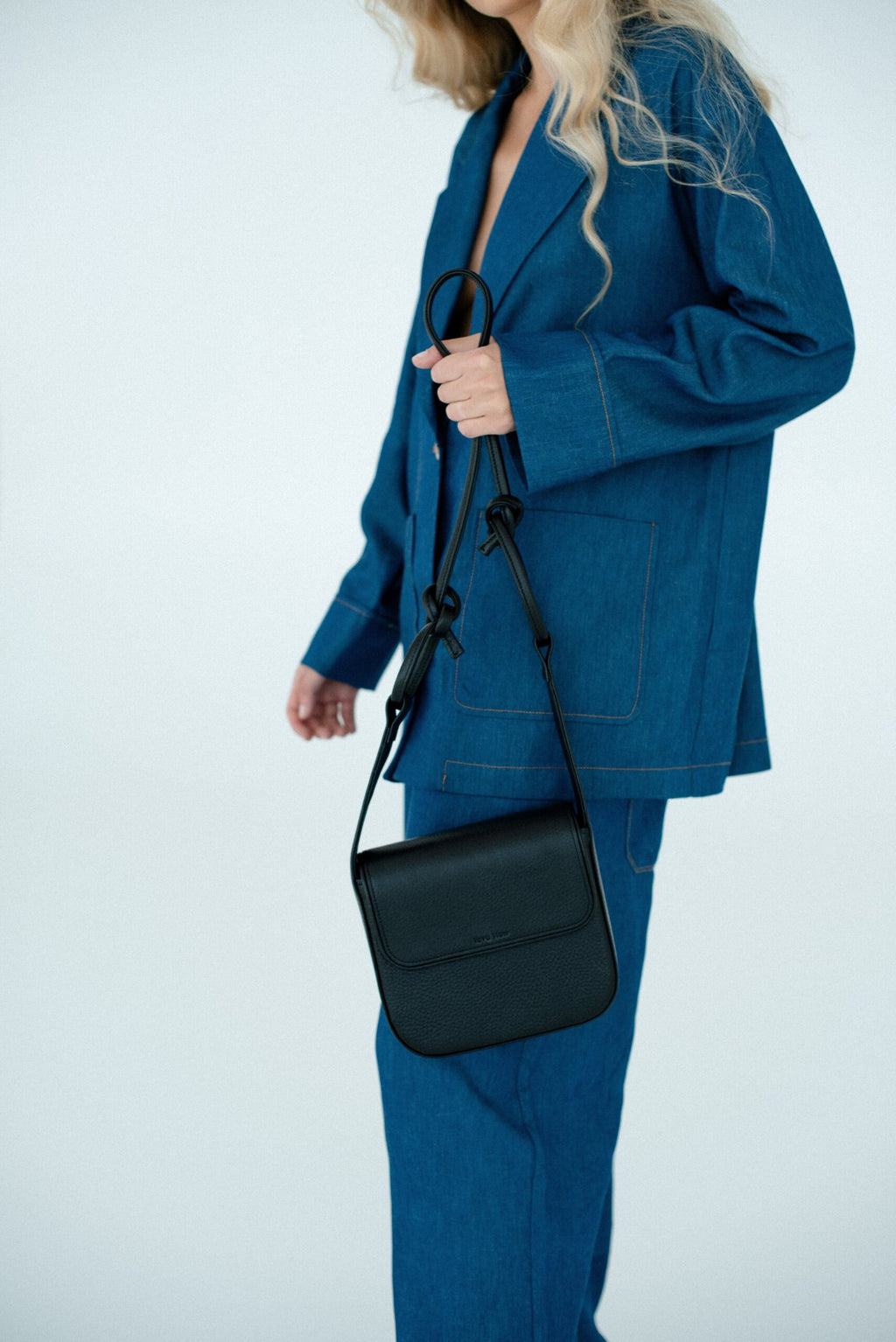 1. Women's black MUSA crossbody bag by Lava Flow, styled with blue denim outfit, shown in lifestyle setting
