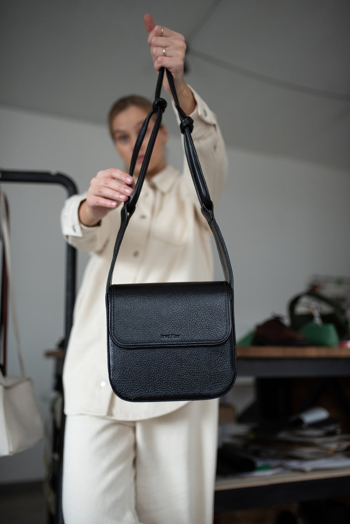 5. Black MUSA crossbody bag by Lava Flow, held by model in cream outfit, studio setting