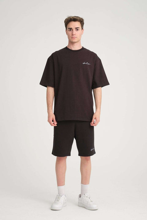 1. Man wearing black sweat shorts and matching t-shirt with white sneakers, standing in studio setting