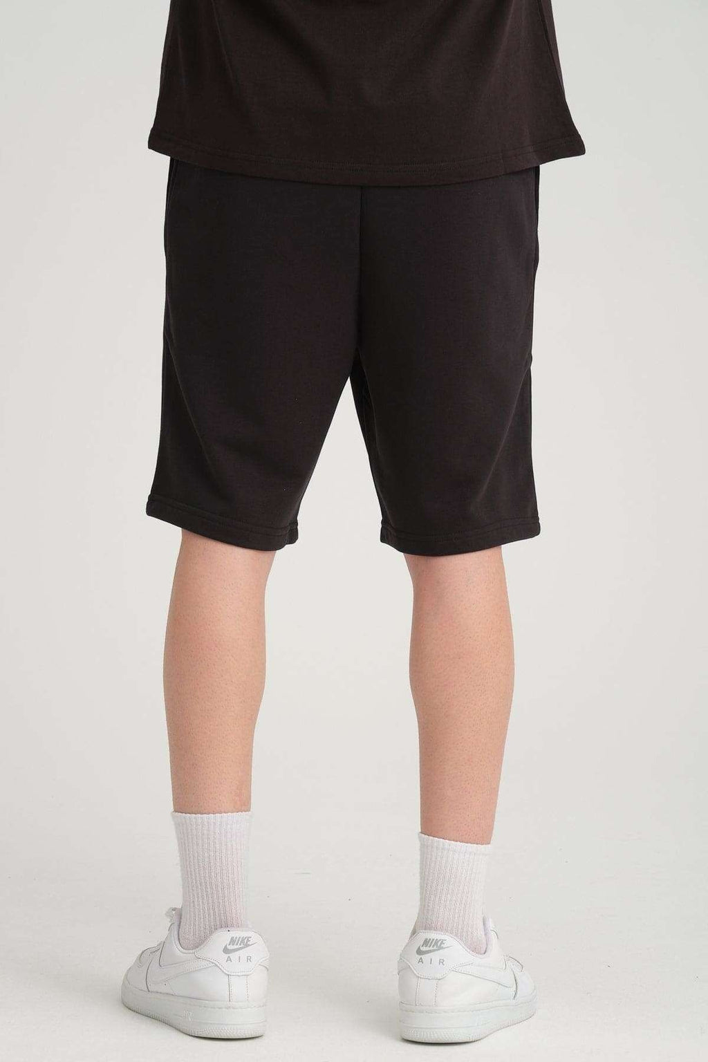 4. Back view of black sweat shorts worn by a man, showing fit and length