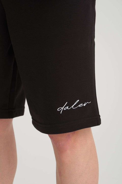 3. Close-up of black sweat shorts with white 'daler' logo embroidery on the leg, highlighting fabric texture and design