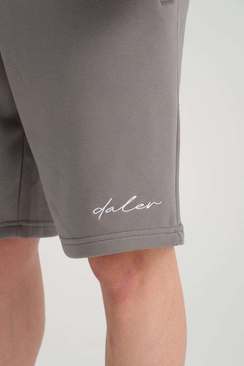3. Close-up of white logo embroidery on grey sweat shorts leg