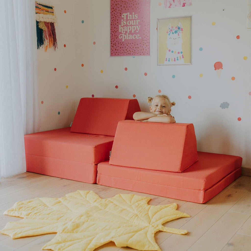 1. Child playing on coral activity play mattress set with trapezoidal pillows in a colorful room