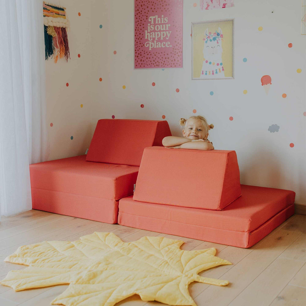 1. Child playing on coral activity play mattress set with trapezoidal pillows in a colorful room