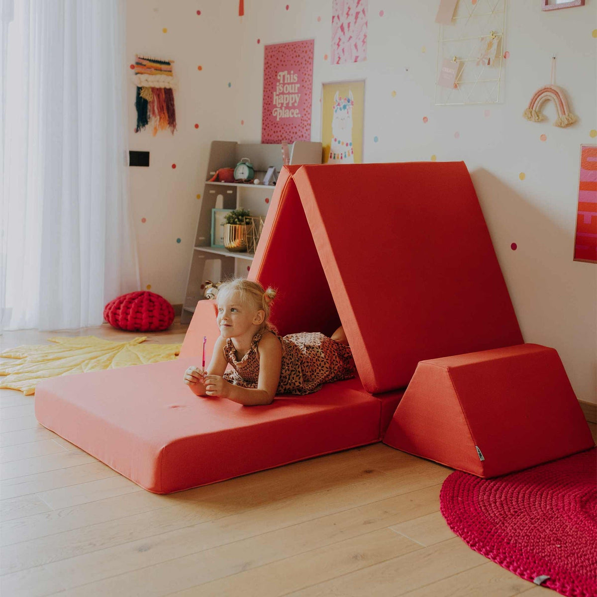 7. Child lying on coral activity play mattress set arranged as a tent in a colorful room