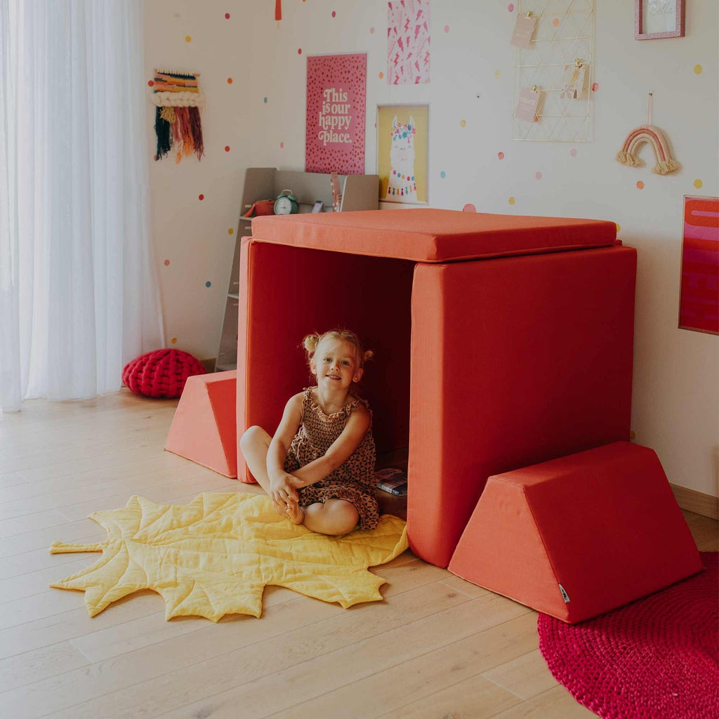 3. Child sitting inside a playhouse made from coral activity play mattress set in a playful room
