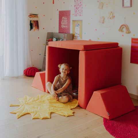 3. Child sitting inside a playhouse made from coral activity play mattress set in a playful room