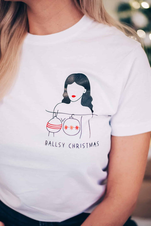 3. Close-up of white T-shirt with 'Ballsy Christmas' print featuring minimalist illustration of woman holding ornaments, made from organic cotton