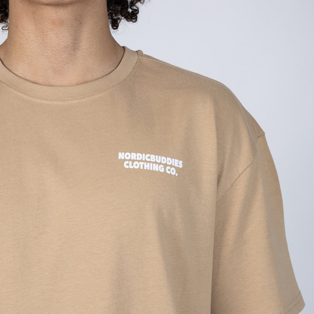 6. Close-up of NordicBuddies logo on beige Moomin t-shirt, showcasing organic cotton fabric