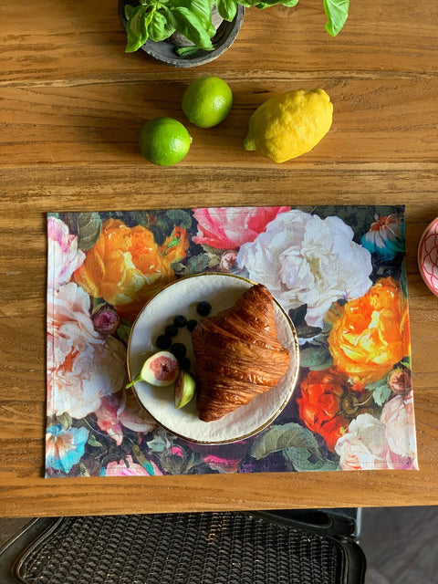 2. Close-up of floral printed placemat with croissant and fruit on wooden table, showcasing colorful design