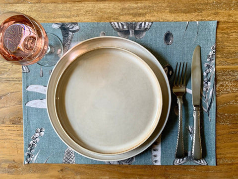 1. Table setting with Hortensias Home Seeds Aqua placemat featuring a ceramic plate, cutlery, and a glass of rosé on a wooden table