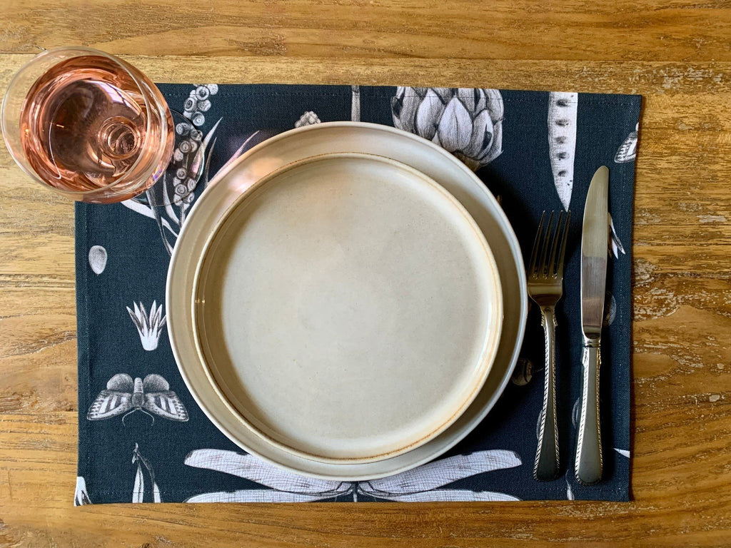 1. Dining table setting with beige plate, cutlery, and pink drink on black Seeds Carbon print cotton placemat by Hortensias Home