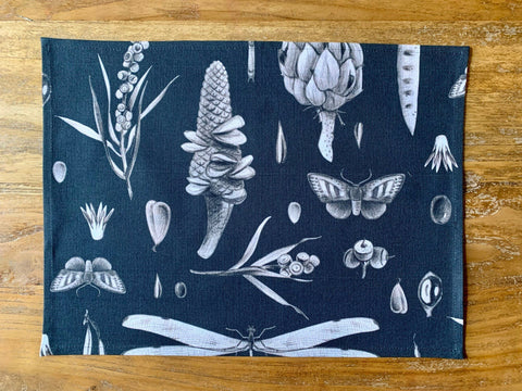 2. Studio shot of black Seeds Carbon print cotton placemat by Hortensias Home featuring botanical and insect illustrations