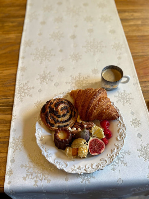 4. Golden Snowfall table runner on wooden table with pastries and coffee, highlighting elegant snowflake design