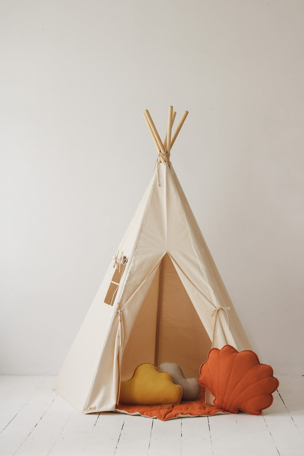 1. Beige teepee tent with window and open entrance, decorated with orange and yellow cushions, in a studio setting