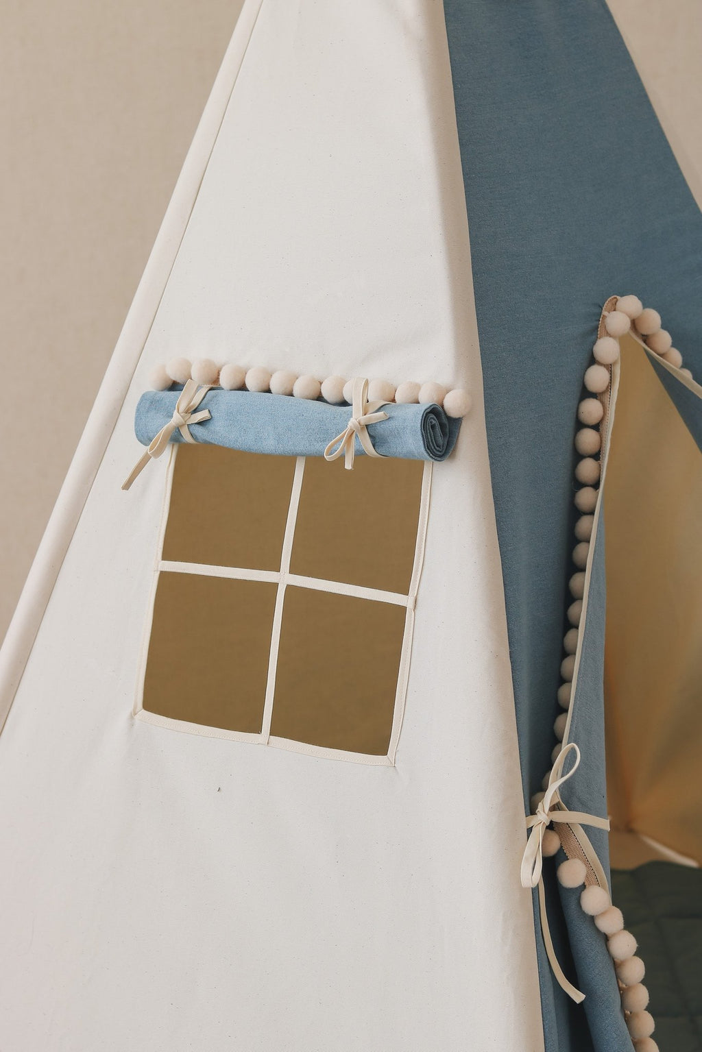 5. Close-up of blue and white teepee tent window with rolled curtain and pompoms, highlighting fabric detail.