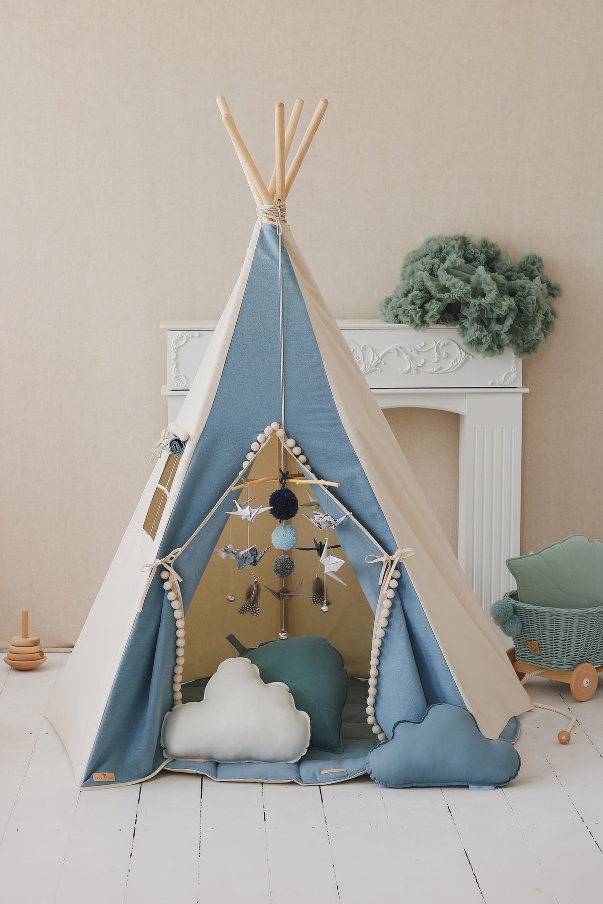 3. Blue and white children's teepee tent with pompoms, decorated with cloud pillows and hanging ornaments, in a cozy room setting.