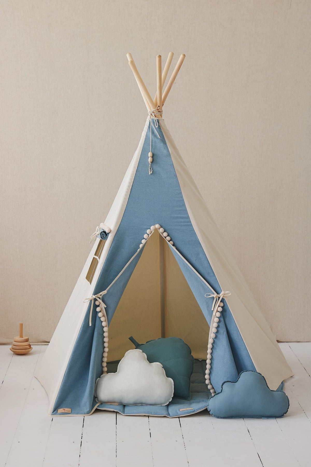4. Blue and white children's teepee tent with pompoms, featuring cloud pillows inside, on white floor with beige background.