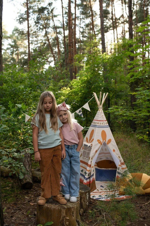 1. Two girls standing beside a teepee tent with Native Vibe print in a forest setting