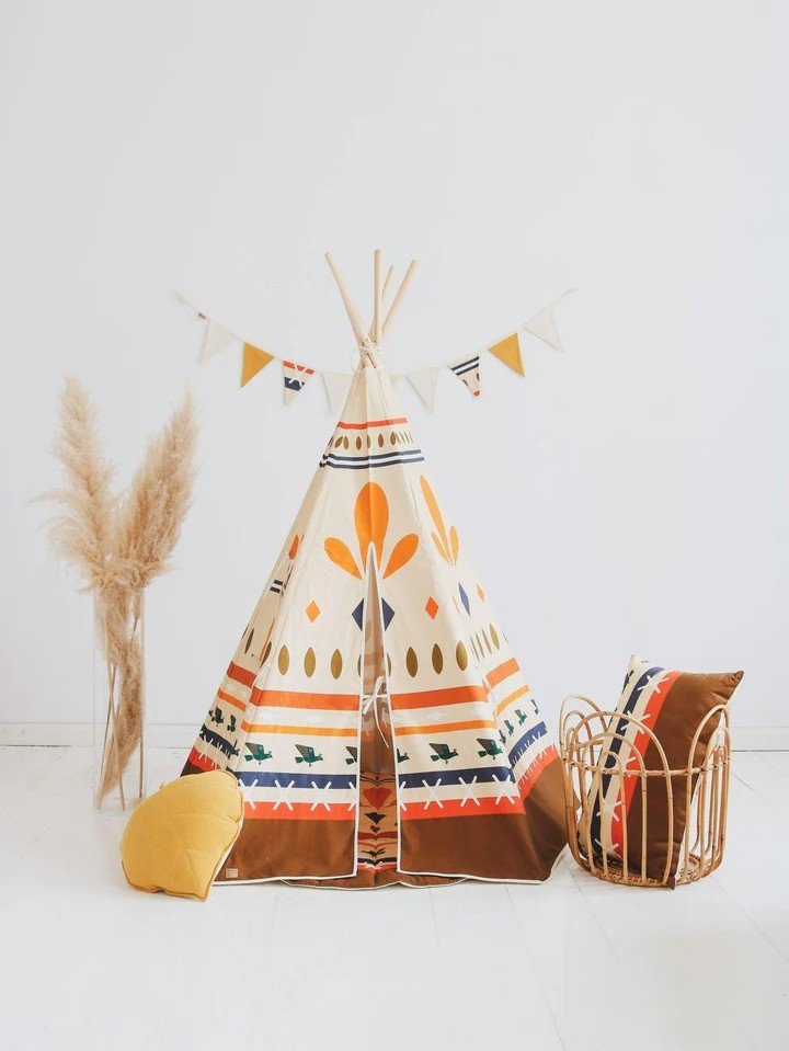 2. Teepee tent with geometric prints and decorative pillows in a bright room with pampas grass