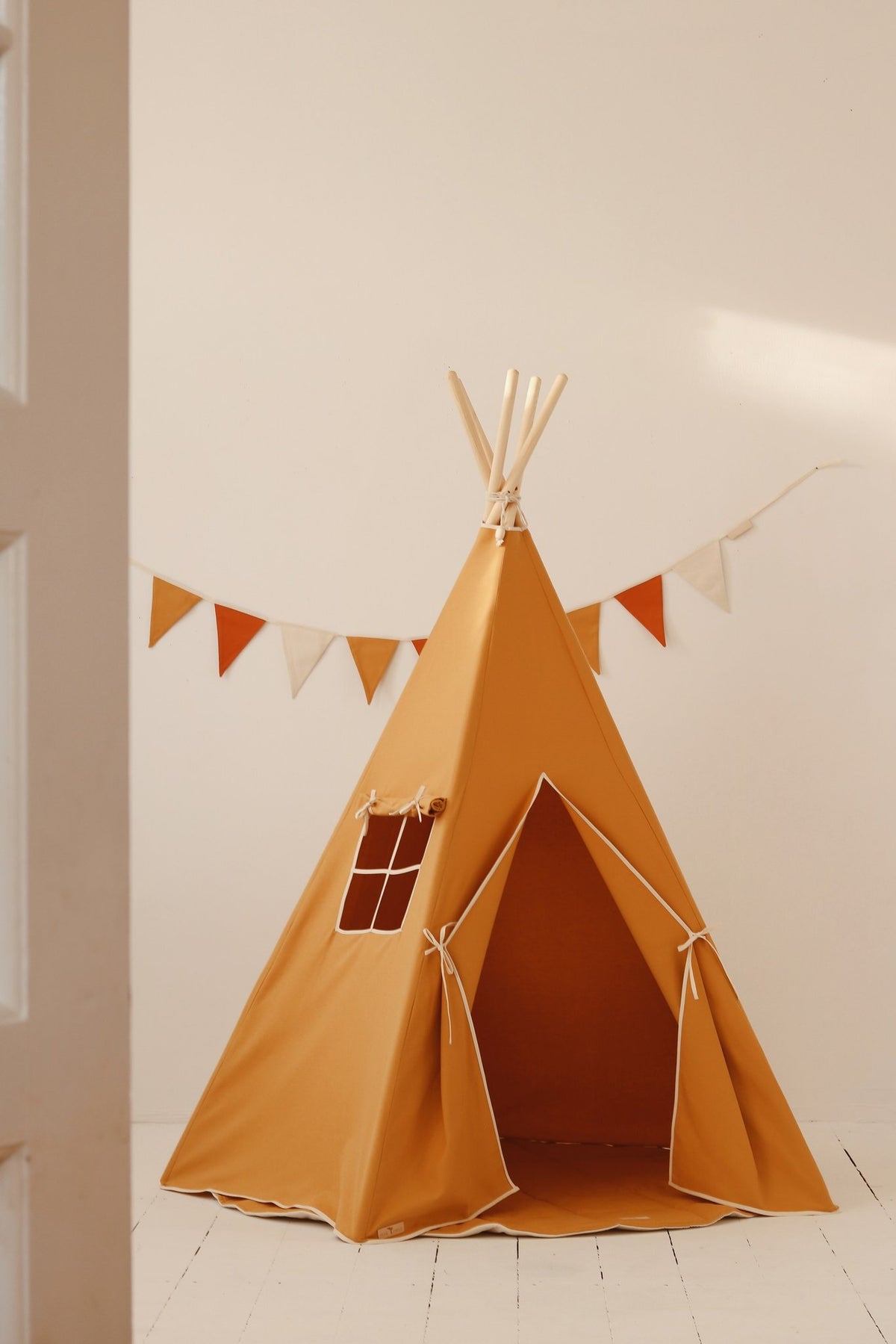 1. Orange teepee tent in a bright room with bunting, showcasing play space for children