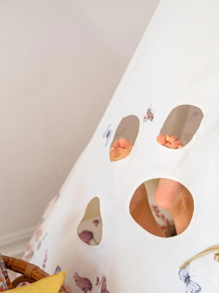 5. Close-up of children's teepee tent with cut-out windows, showing playful feet inside, featuring floral and bee design